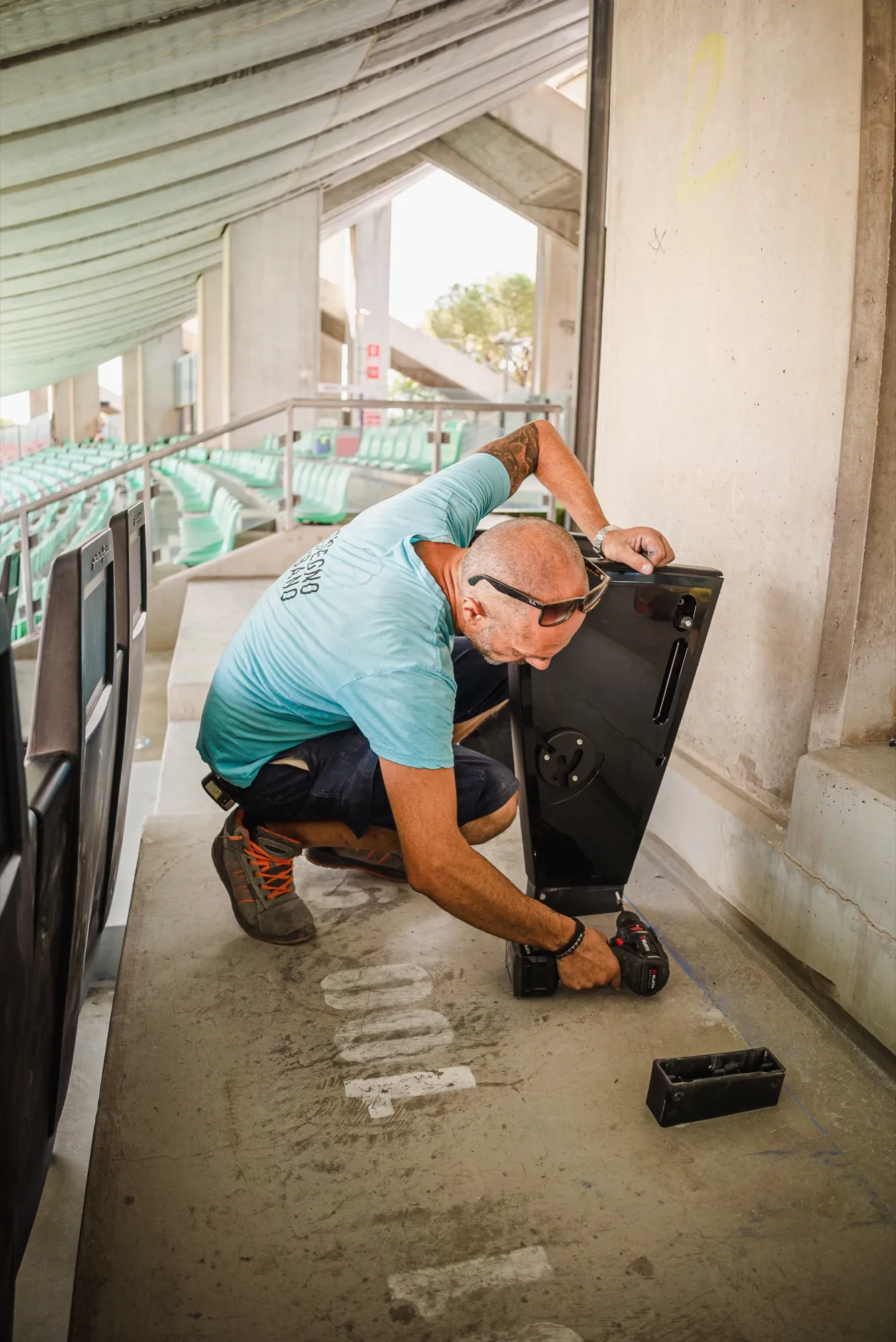 Un tecnico di Disegno Urbano installa una seduta alla tribuna dello Stadio San Nicola