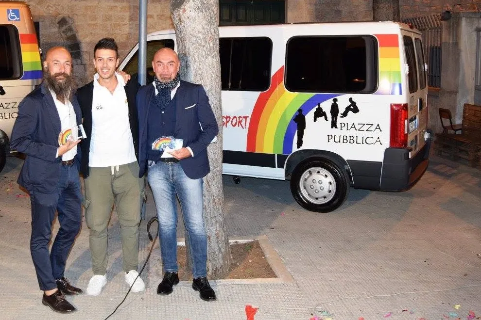 Di sera, con in mano le targhe di ringraziamento agli sponsor, davanti ai due pulmini consegnati all'Unitalsi e sotto lo striscione di Piazza Pubblica.